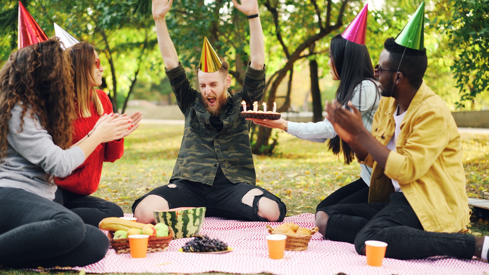 Freunde feiern einen Geburtstag mit Kuchen im Park